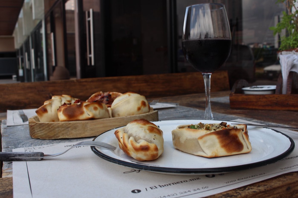 Mesa con empanadas al horno y copa de vino en El Hornero
